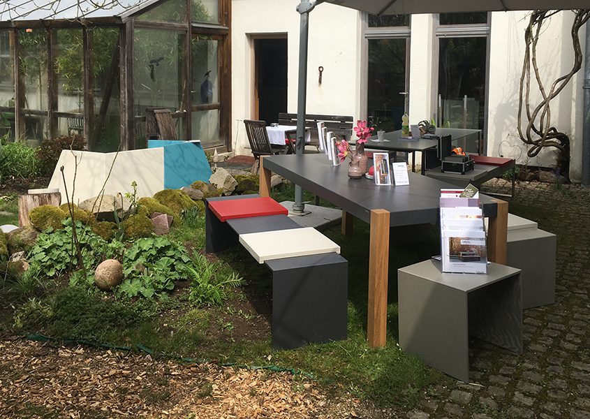 Gartenterrasse mit Betontisch mit Holzfüßen und schlanker Betonbank und Betonhocker